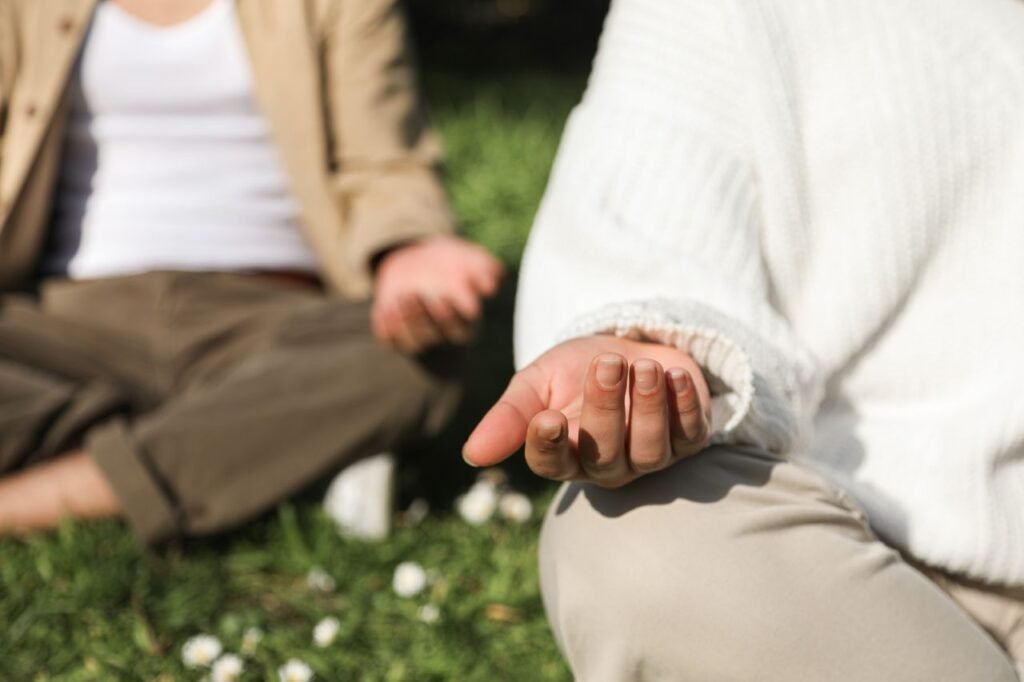 pexels-photo-6962655-6962655 Two people meditating outdoors, focusing on hands in a peaceful setting.